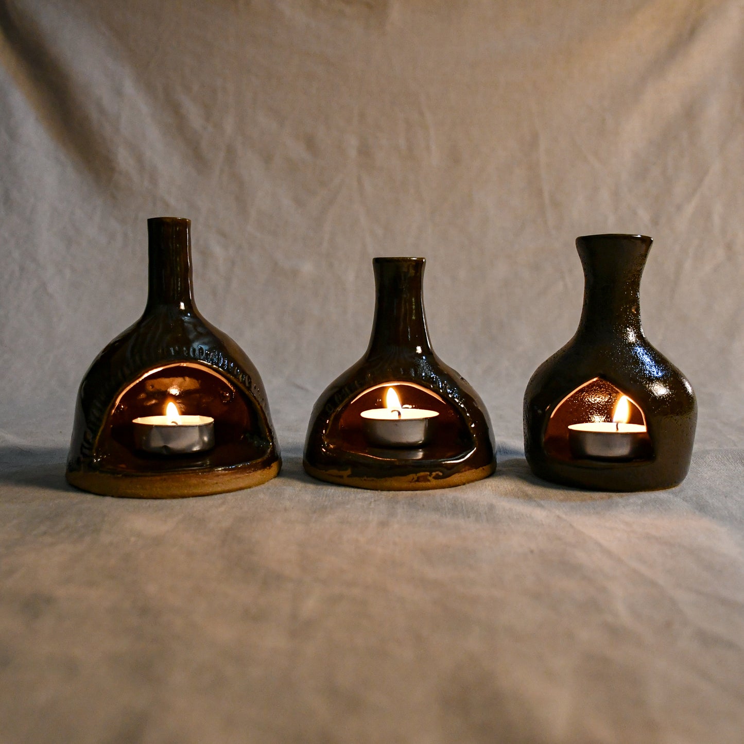 Lit handmade countertop chimineas, wheel thrown, hand-carved, fit for a tea lights and glazed in Coffee Bean glaze.