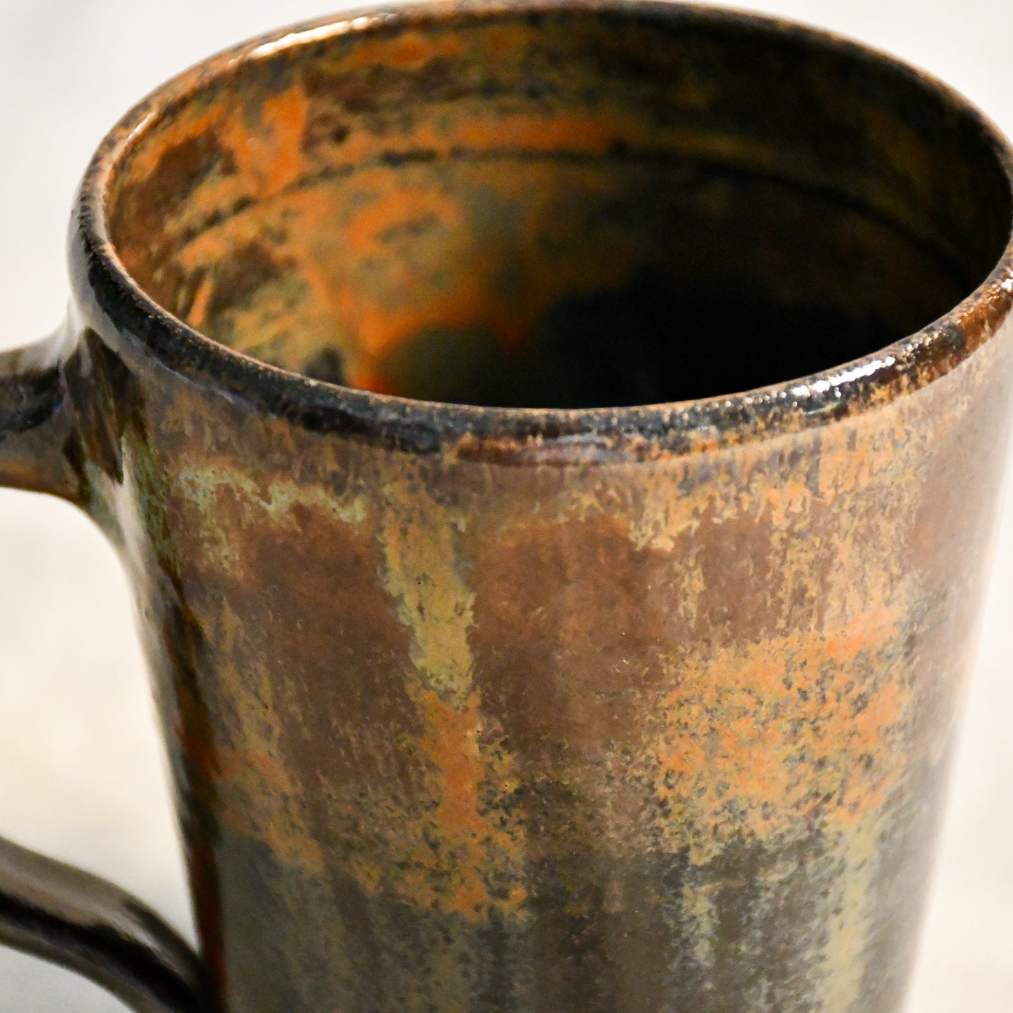Detailed view of the Ancient Jasper glaze on a handcrafted ceramic mug, showcasing organic rust, olive, charcoal, and brown textures.