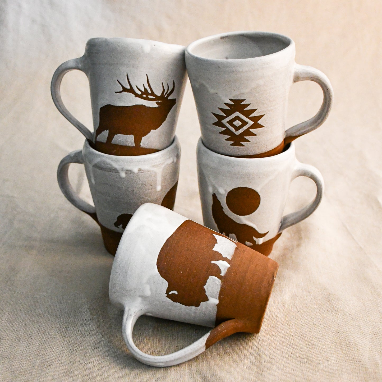 Set of four ceramic mugs with animal-themed designs on a beige background