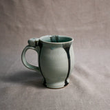 Pale blue handmade pottery mug with black drips from the 5th Buffalo collection by Leigh Art
