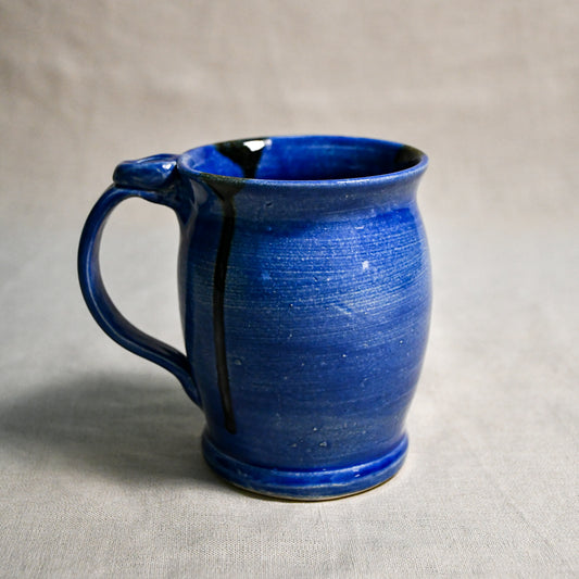Blue handmade pottery mug with black drips from the 5th Buffalo collection by Leigh Art