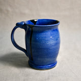 Blue handmade pottery mug with black drips from the 5th Buffalo collection by Leigh Art