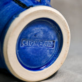 Bottom view close up of blue handmade mug showing trimmed fired ceramic foot and texture.