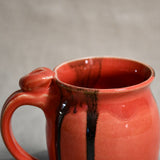 Close up of rim and handle of coral handmade mug with stamped thumbrest, black drips and showing texture