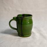 Green handmade pottery mug with black drips from the 5th Buffalo collection by Leigh Art