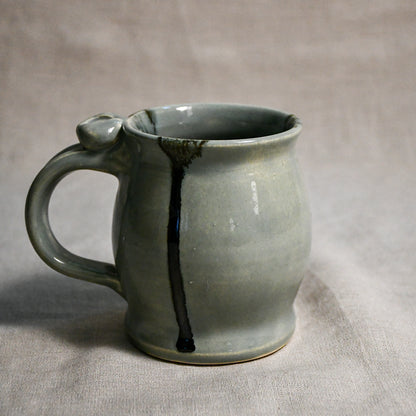 Grey handmade pottery mug with black drips from the 5th Buffalo collection by Leigh Art