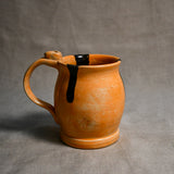 Orange handmade pottery mug with black drips from the 5th Buffalo collection by Leigh Art