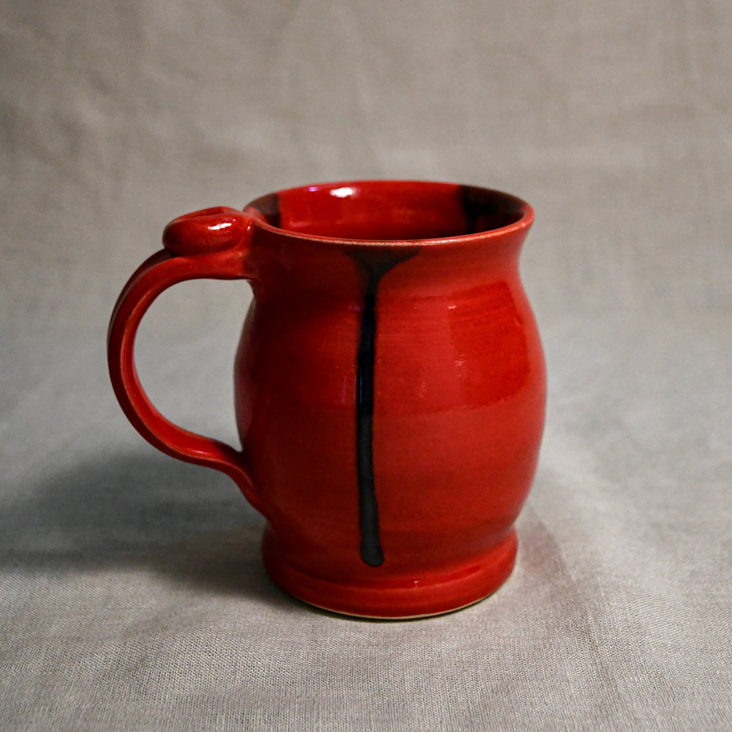Red handmade pottery mug with black drips from the 5th Buffalo collection by Leigh Art