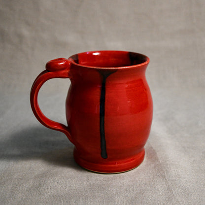 Red handmade pottery mug with black drips from the 5th Buffalo collection by Leigh Art