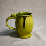Lime green handmade pottery mug with black drips from the 5th Buffalo collection by Leigh Art