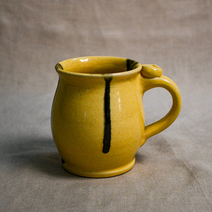 Yellow handmade pottery mug with black drips from the 5th Buffalo collection by Leigh Art