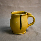 Yellow handmade pottery mug with black drips from the 5th Buffalo collection by Leigh Art