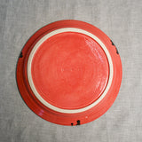 Bottom view of a coral ceramic dinner plate showing exposed stoneware clay and texture