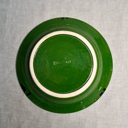Bottom view of a green ceramic dinner plate showing exposed stoneware clay and texture