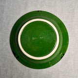Bottom view of a green ceramic dinner plate showing exposed stoneware clay and texture