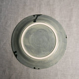 Bottom view of a grey ceramic dinner plate showing exposed stoneware clay and texture