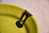 Close up of a lime green ceramic dinner plate showing black drips and texture