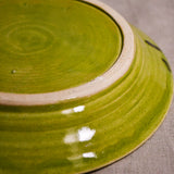 Close up of bottom of a lime green ceramic dinner plate showing exposed stoneware clay foot and texture