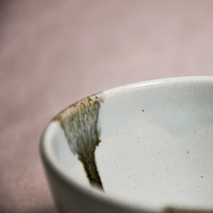 Close up of pale blue handmade wheelthrown pottery salsa bowl from the 5th Buffalo collection by Leigh Art showing black drips and texture. 