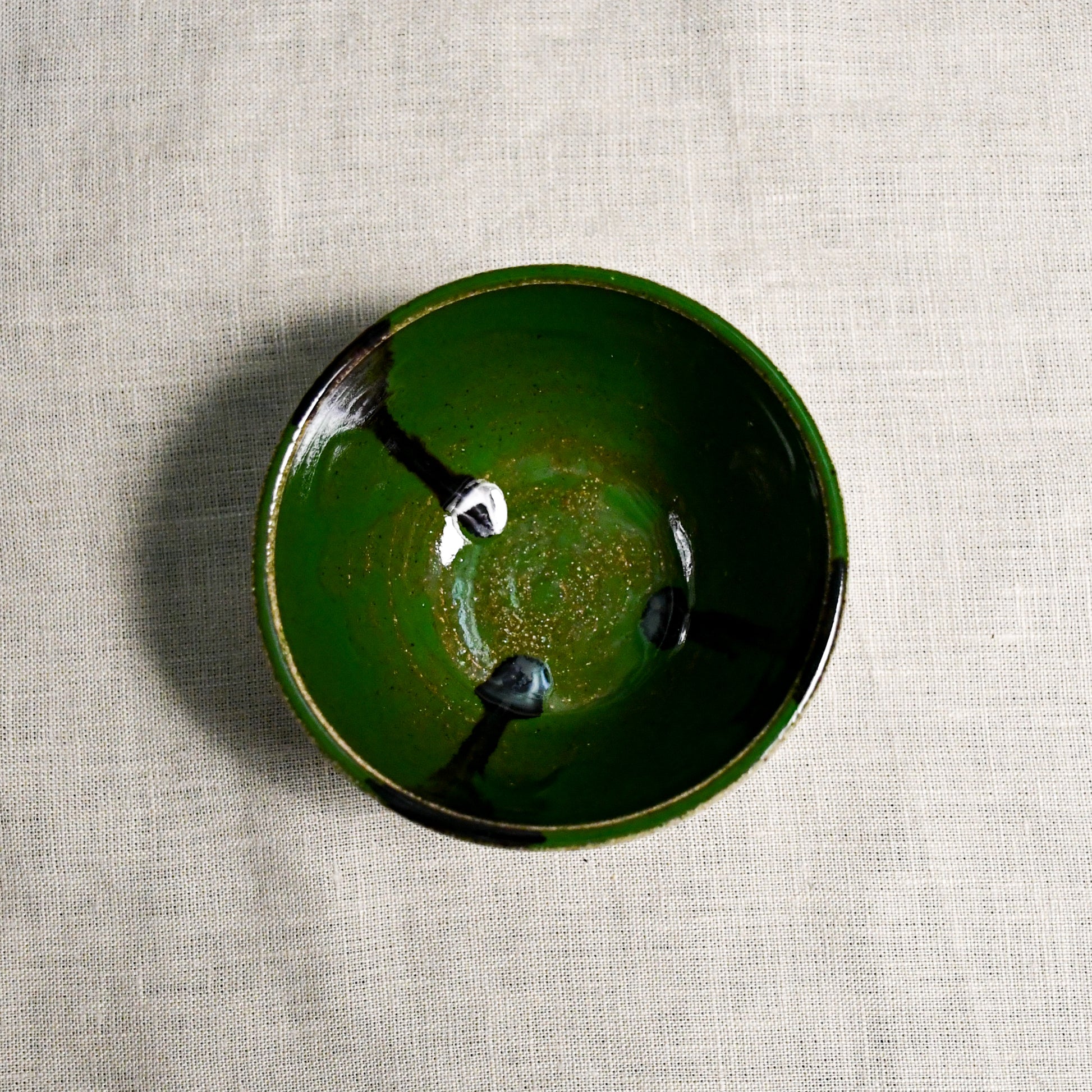 Interior image of a green handmade wheelthrown salsa bowl with black drips from the 5th Buffalo collection by Leigh Art.