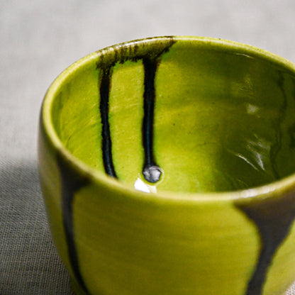 Close up of lime green handmade wheelthrown pottery salsa bowl from the 5th Buffalo collection by Leigh Art showing black drips and texture. 
