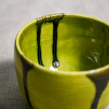 Close up of lime green handmade wheelthrown pottery salsa bowl from the 5th Buffalo collection by Leigh Art showing black drips and texture. 