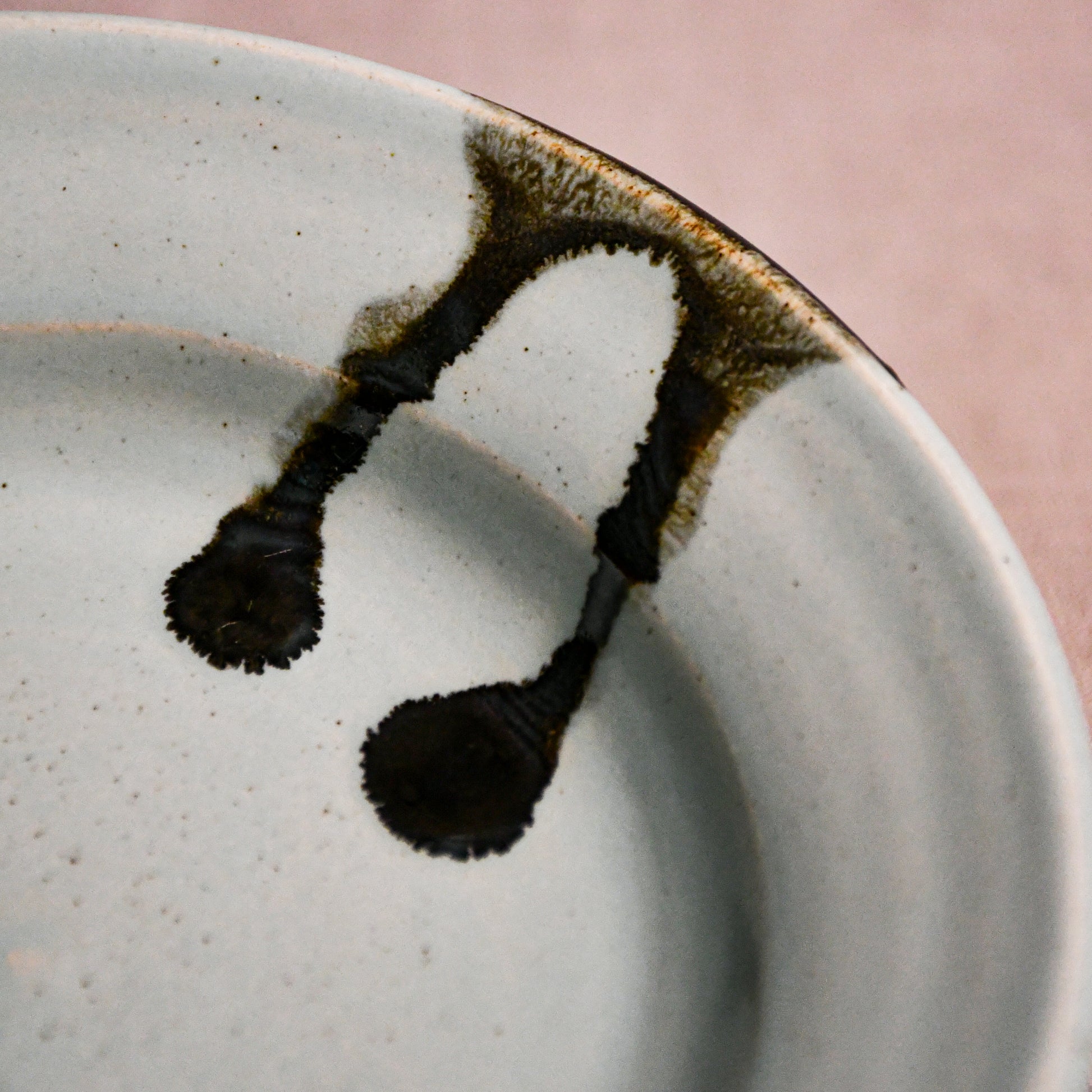 Close up of pale blue handmade wheelthrown pottery saucer with black drips from the 5th Buffalo collection by Leigh Art