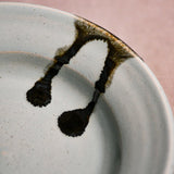 Close up of pale blue handmade wheelthrown pottery saucer with black drips from the 5th Buffalo collection by Leigh Art