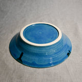 Close up of bottom of a turquoise ceramic saucer showing exposed stoneware clay foot and texture