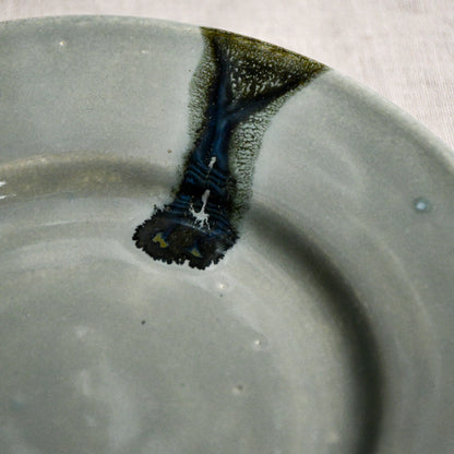 Close up of grey handmade wheelthrown pottery saucer with black drips from the 5th Buffalo collection by Leigh Art