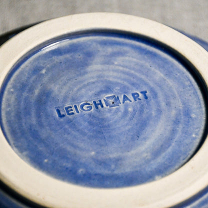 Close up of bottom of a purple ceramic saucer showing exposed stoneware clay foot and texture