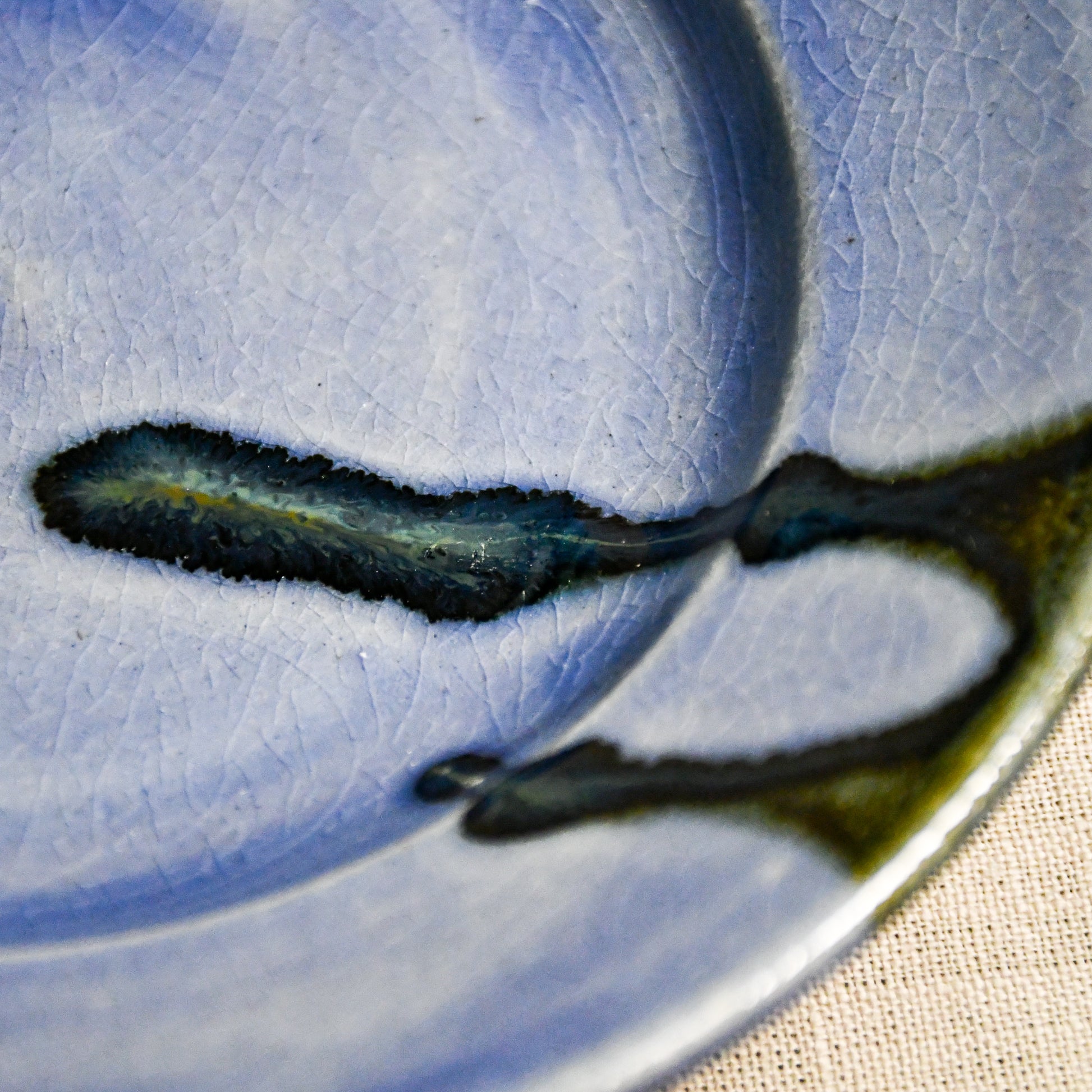 Close up of purple handmade wheelthrown pottery saucer with black drips and crazing from the 5th Buffalo collection by Leigh Art