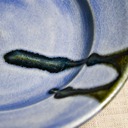 Close up of purple handmade wheelthrown pottery saucer with black drips and crazing from the 5th Buffalo collection by Leigh Art