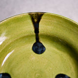 Close up of lime green handmade wheelthrown pottery saucer with black drips from the 5th Buffalo collection by Leigh Art