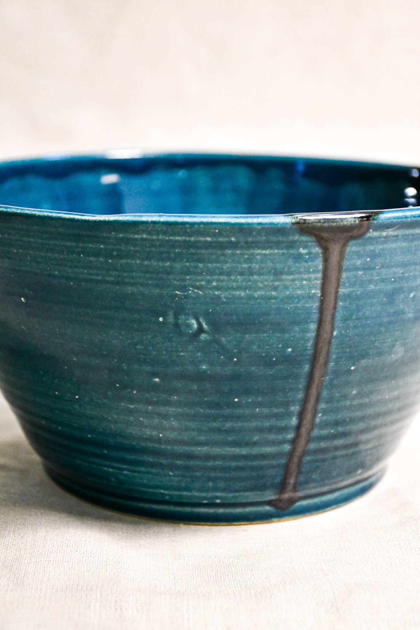 Close up of dark teal handmade wheelthrown serving bowl with black drips from the 5th Buffalo collection from Leigh Art. 