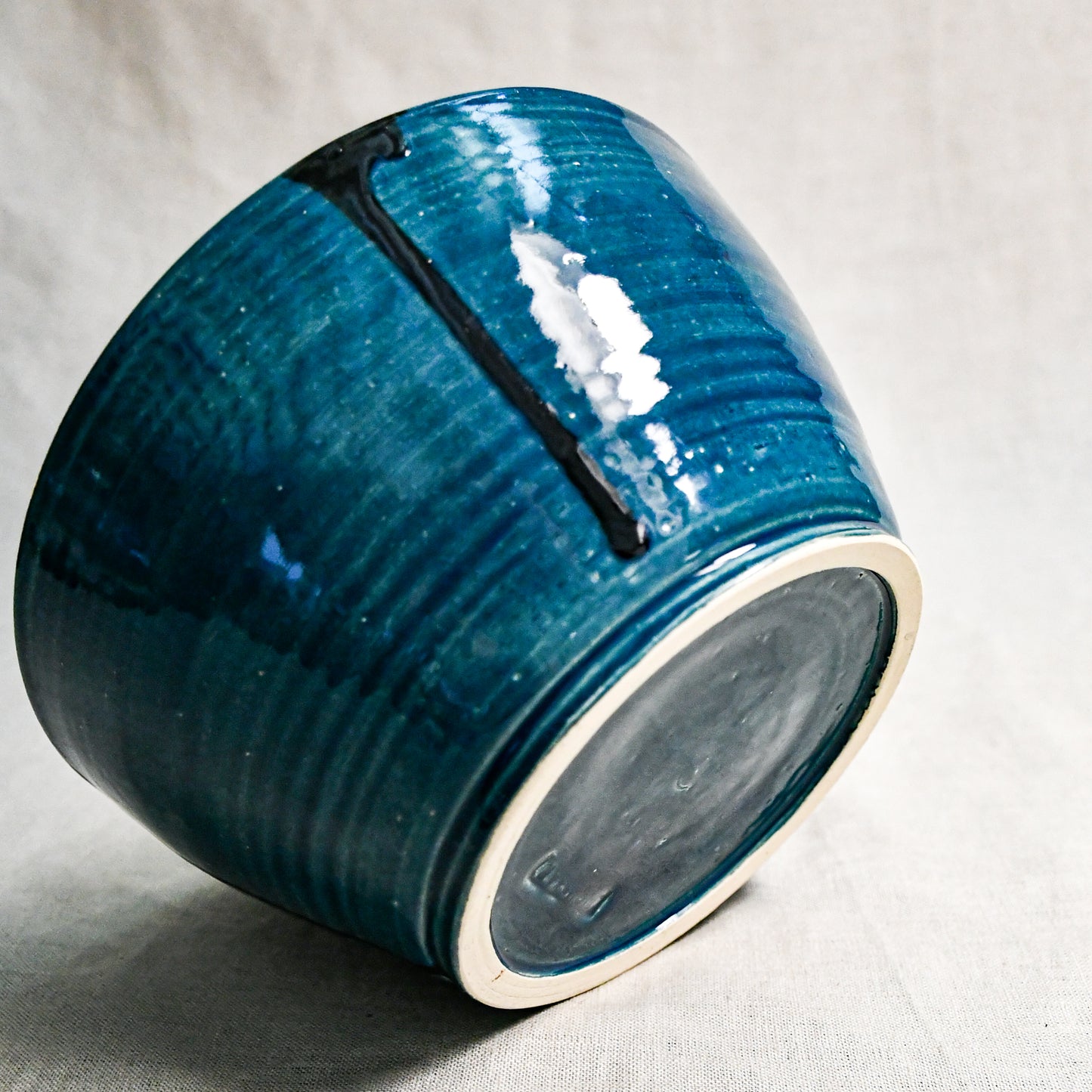 Bottom view of dark teal handmade wheelthrown serving bowl with black drips and texture from the 5th Buffalo collection from Leigh Art. 