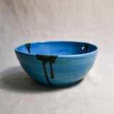 Side view of turquoise handmade wheelthrown serving bowl with black drips from the 5th Buffalo collection from Leigh Art. 