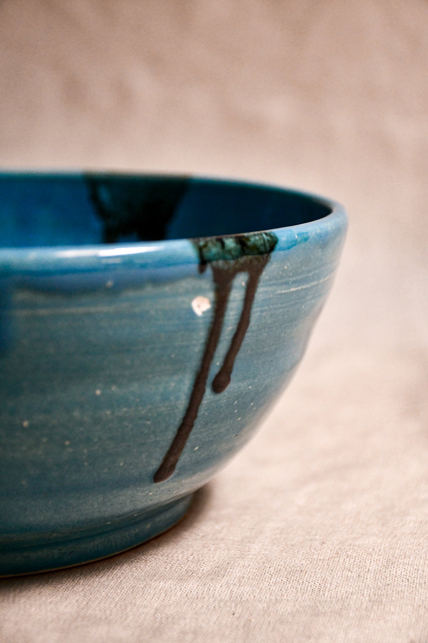 Close up of turquoise handmade wheelthrown serving bowl with black drips from the 5th Buffalo collection from Leigh Art. 