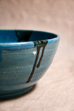 Close up of turquoise handmade wheelthrown serving bowl with black drips from the 5th Buffalo collection from Leigh Art. 