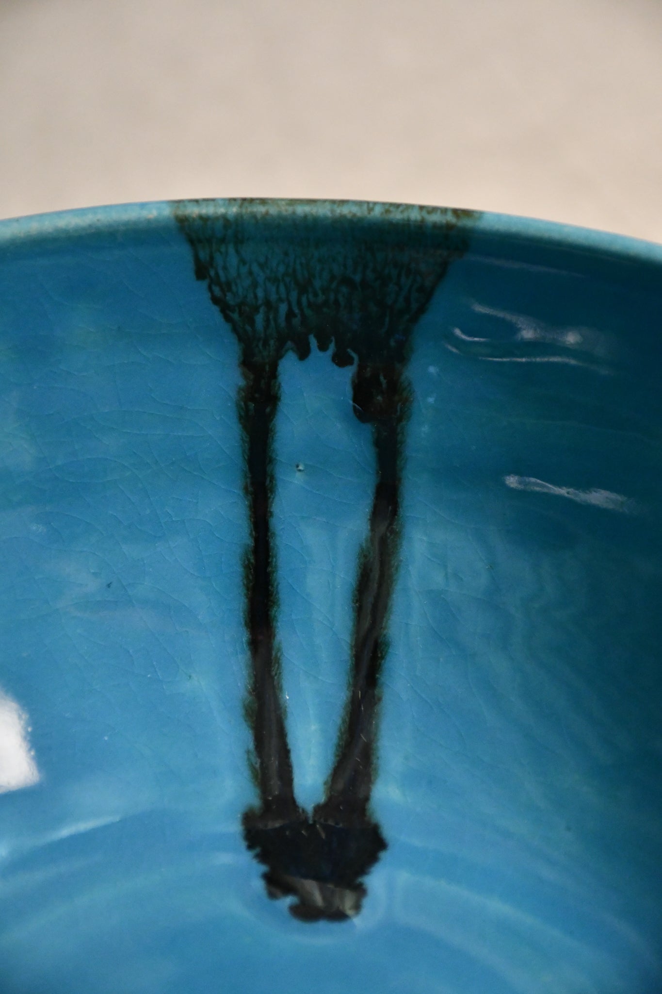 Close up of turquoise handmade wheelthrown serving bowl with black drips from the 5th Buffalo collection from Leigh Art. 