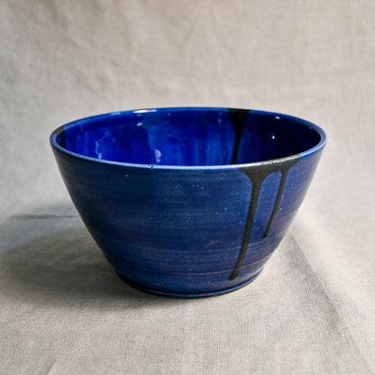 Side view of turquoise handmade wheelthrown serving bowl with black drips from the 5th Buffalo collection from Leigh Art. 