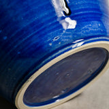 Close up of blue handmade wheelthrown serving bowl with black drips from the 5th Buffalo collection from Leigh Art. 