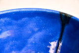Close up of blue handmade wheelthrown serving bowl with black drips and crazing from the 5th Buffalo collection from Leigh Art. 