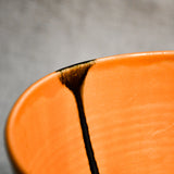 Close up of orange handmade wheelthrown serving bowl with black drips and texture from the 5th Buffalo collection from Leigh Art. 