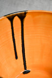 Close up of orange handmade wheelthrown serving bowl with black drips from the 5th Buffalo collection from Leigh Art. 