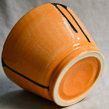 Bottom view of orange handmade wheelthrown serving bowl with black drips from the 5th Buffalo collection from Leigh Art. 