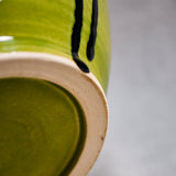 Close up bottom view of lime green handmade wheelthrown serving bowl with black drips from the 5th Buffalo collection from Leigh Art. 
