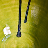 Close up of lime green handmade wheelthrown serving bowl with black drips and texture from the 5th Buffalo collection from Leigh Art. 