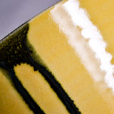 Close up of yellow handmade wheelthrown serving bowl with black drips and crazing from the 5th Buffalo collection from Leigh Art. 