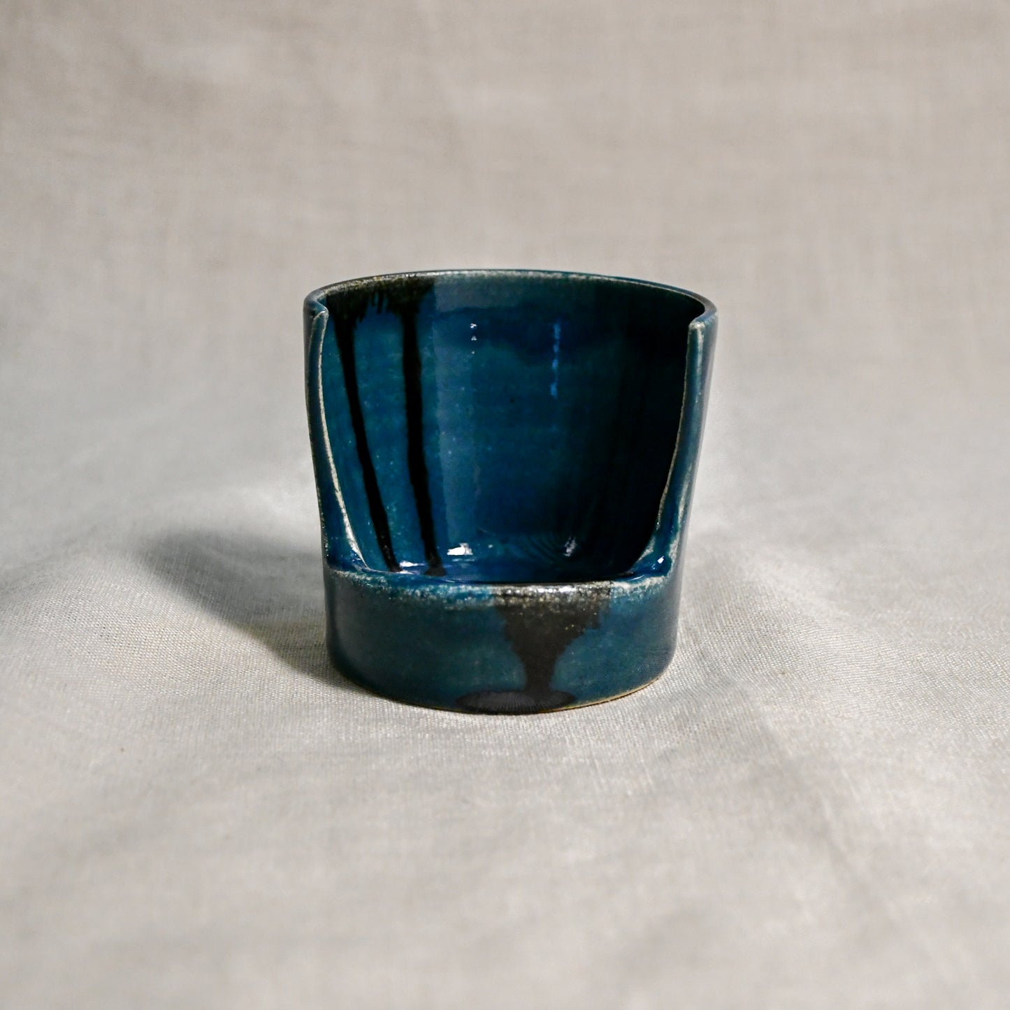 Close up of dark teal vertical handmade pottery spoon rest from the 5th Buffalo collection by Leigh Art with black drips